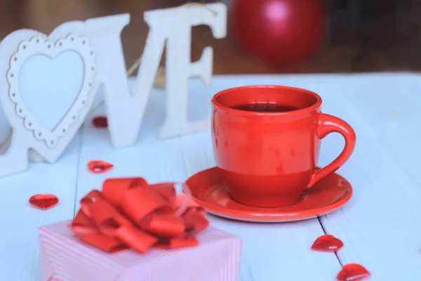 Tazza di caffè e regalo su sfondo sfocato . — Foto Stock