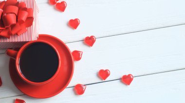 Ahşap masa üzerinde kırmızı kahve Kupası ve hediye kutusu