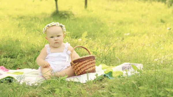 Cute baby in a wreath on a picnic on a summer day. — Stock Photo, Image