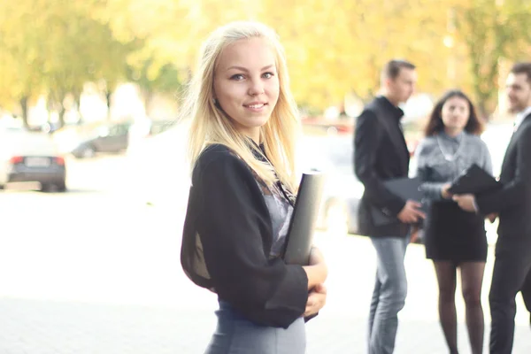 young business woman with clipboard standing outdoors near office