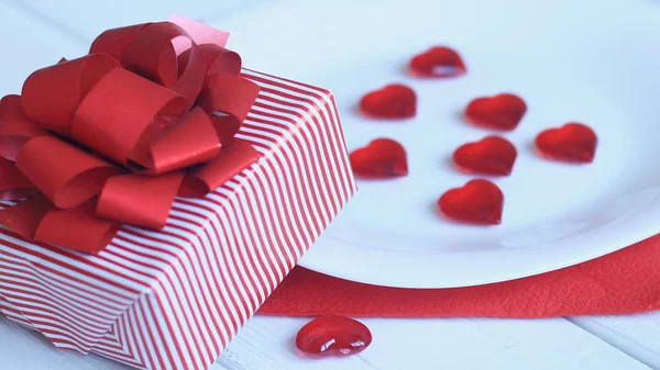 Close up. Red hearts on white plate and gift box on light background — стоковое фото