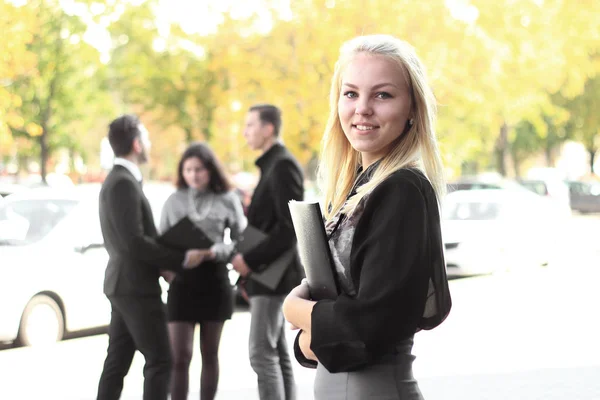 young business woman with clipboard standing outdoors near office