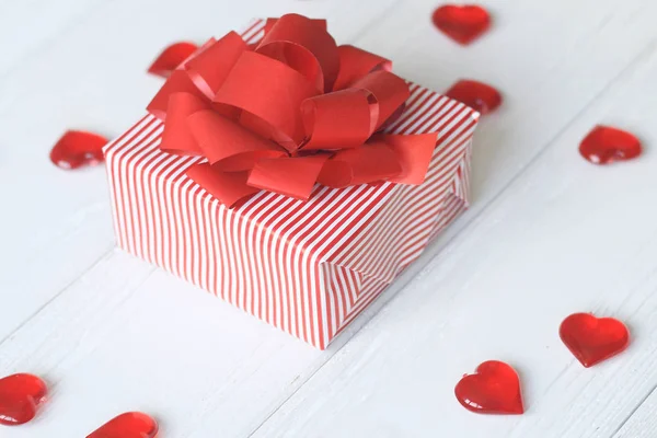 Confezione regalo con fiocco rosso e cuori su sfondo chiaro — Foto Stock