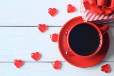 Ahşap masa üzerinde kırmızı kahve Kupası ve hediye kutusu