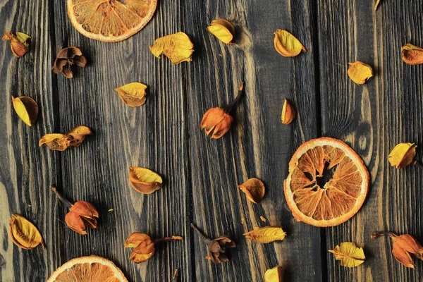 Orangenscheiben und Blütenblätter aus getrockneten Blumen auf hölzernem Hintergrund — Stockfoto