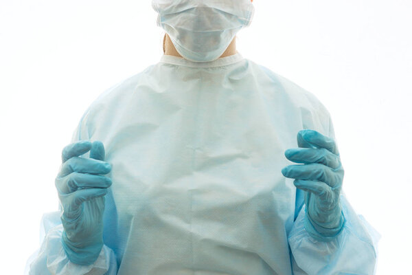 Хирург в стерильном платье, хирургической маске и перчатках готов к работе

