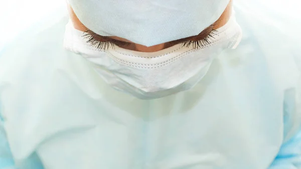 Fluffy eyelashes of surgeon in sterile surgical mask and medical gown at work