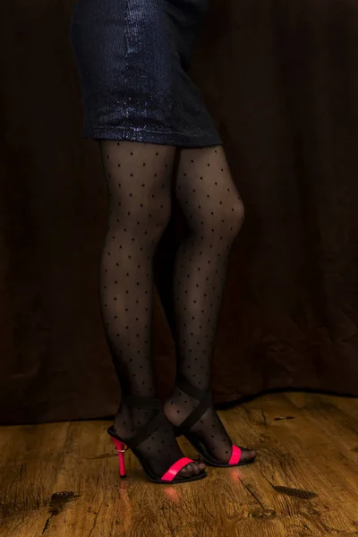 Slender legs of girl in fashionable black tights with black dots and high heels