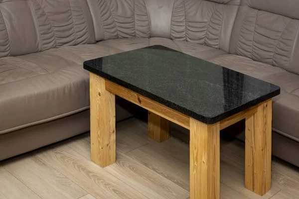 Empty rustic table made of polished granite by a soft leather sofa