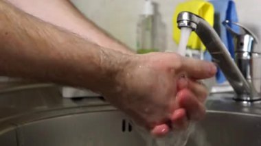 Adam ellerini dikkatlice musluğun altında sabunluyor. Hijyen için suyla.
