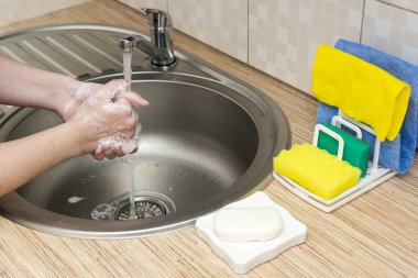 Kadınlar mutfakta sabun ve musluk suyuyla ellerini iyi yıkarlar.