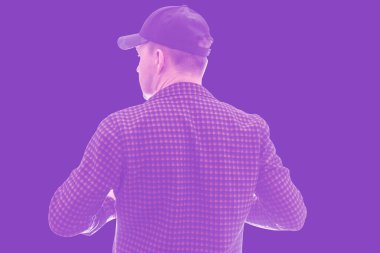 Beyzbol şapkalı ve ekose gömlekli bir adam arkasında duruyor.