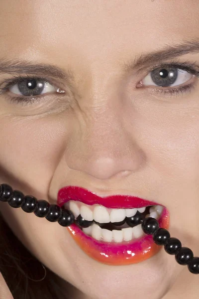 Biting her teeth on a string of beads — Stock Photo, Image