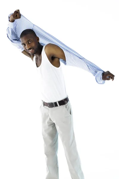 African male enjoyably taking off his shirt while looking at the Stock Photo