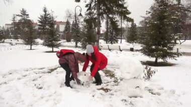 kız ve oğlan bir kardan adam şehirde Park yapmak
