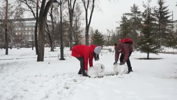 Flicka bror och göra en snögubbe — Stockvideo