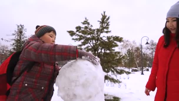 Fratello e sorella scolpire pupazzo di neve nel parco — Video Stock