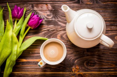 Bir fincan kahve ile bir çaydanlık ve çiçekler