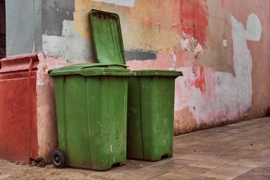 İki yeşil çöp bidonları çok renkli duvar eski yakın: