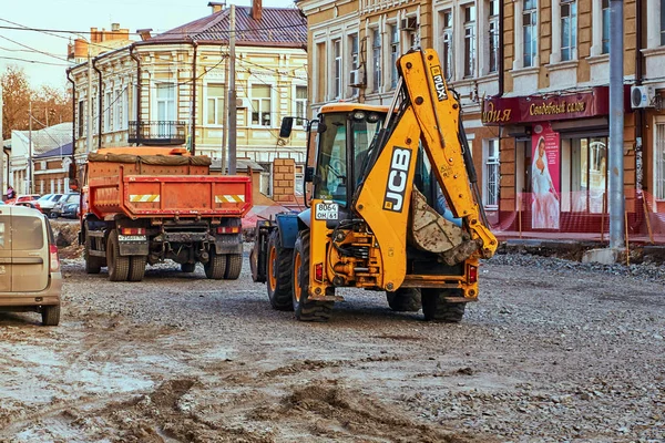 Rostov-on-Don / Ryssland - januari 2018: grävmaskin och dumper i återuppbyggnaden av en gata i centrum av en stor stad — Stockfoto
