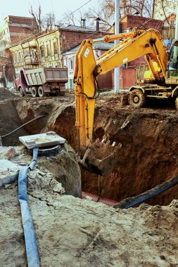 Şehrin büyük bir sarı Ekskavatör bir kova ile bir çukur kazıyor