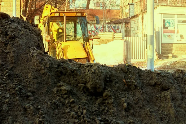 Большой желтый экскаватор в городе выкапывает яму с ведром — стоковое фото