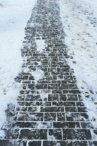 Trottoaren kakel i vintern på ett tunt lager snö som smälte från värmen i stadens kommunikation — Stockfoto