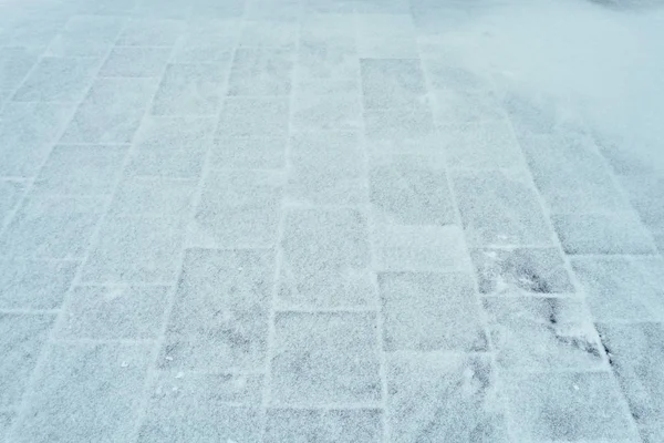 Grå beläggning plattor under ett lager av snö på vintern som bakgrund — Stockfoto