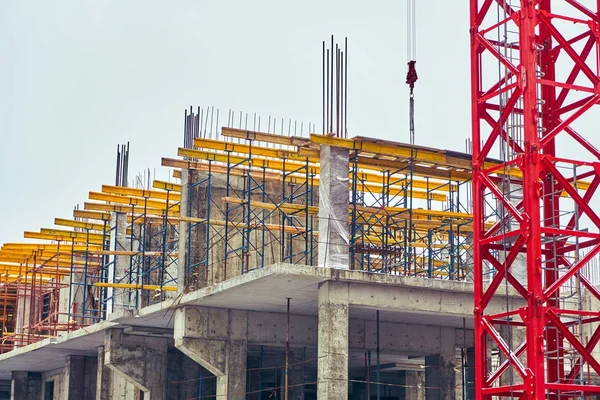 Construção de um novo edifício no inverno na cidade de tijolo e concreto com o uso de um guindaste — Fotografia de Stock