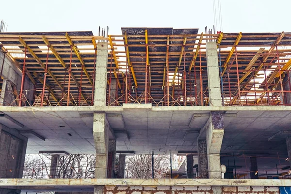 Construção de um novo edifício no inverno na cidade de tijolo e concreto com o uso de um guindaste — Fotografia de Stock