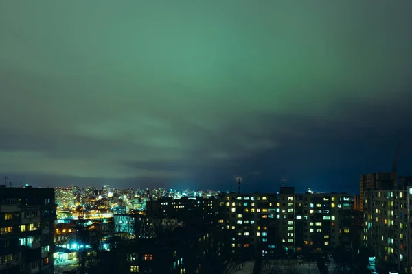 Uma vista da cidade noturna brilhante em lâmpadas e luzes com pequenas nuvens no céu — Fotografia de Stock