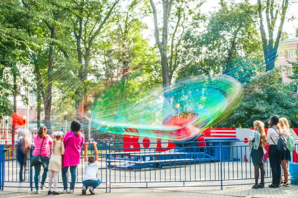 Människor rider på en gunga i en nöjespark på en varm dag — Stockfoto