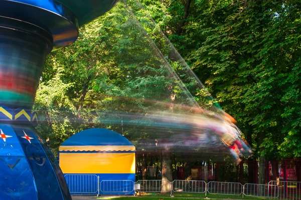 Människor rider på en gunga i en nöjespark på en varm dag — Stockfoto