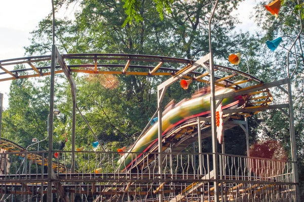 People ride on a roller coaster in an amusement park on a warm d — Stock Photo, Image