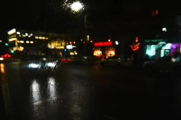 Przez szklane lampki nocne na ulicach miasta, bez ostrości, niewyraźne tło — Zdjęcie stockowe