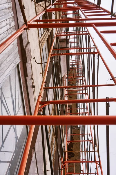 Vecchia impalcatura arancione si trova vicino al vecchio edificio alto per la ricostruzione — Foto Stock