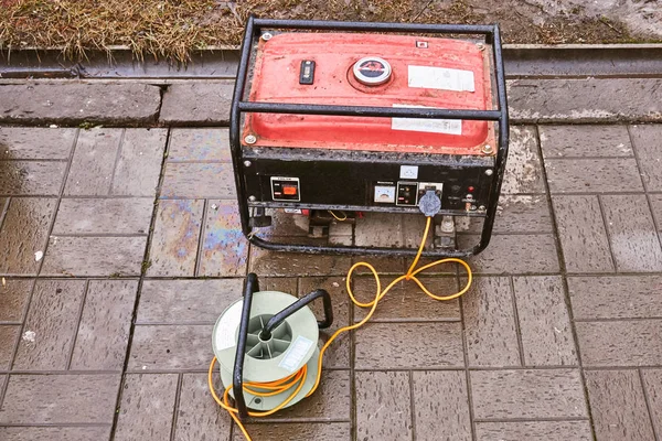 Turuncu bir tel üzerinde sokakta küçük bir kırmızı jeneratör elektrik verir — Stok fotoğraf