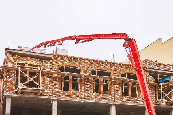 A grande mão vermelha de uma bomba de concreto trabalha na construção de um novo edifício — Fotografia de Stock