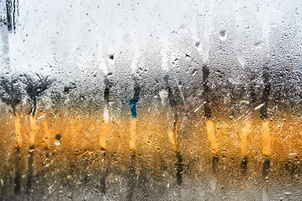 Through the misted glass with raindrops from the outside you can see the wet city