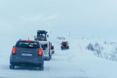 Teriberka, Murmansk bölgesi / Rusya - Şubat 2018: otomobillerin sütun karla kaplı yolu için yol makine içine güçlü bir kar fırtınası boyunca hareket ediyor