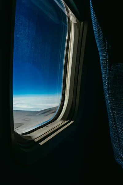 W czasie podróży patrzeć przez iluminator nowych samolotów na błękitne niebo i białe półki — Zdjęcie stockowe