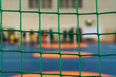 Parlak üniformalı genç futbolcuların kapalı spor kompleksi yakın çekim bir kılavuz ile bir futbol kapı arkasında futbol oynamak