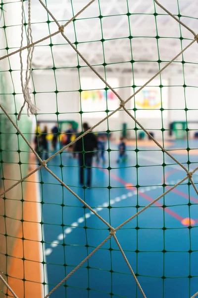Parlak üniformalı genç futbolcuların kapalı spor kompleksi yakın çekim bir kılavuz ile bir futbol kapı arkasında futbol oynamak