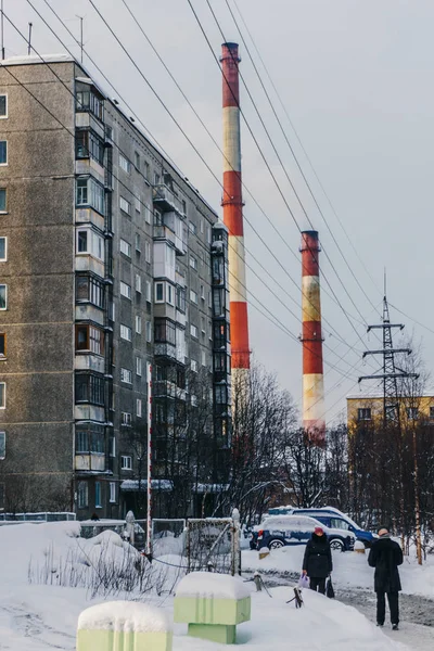 Murmansk, região de Murmansk / Rússia - Fevereiro 2018: Vista de um antigo edifício residencial e tubos altos com fumaça perigosa e moradores locais — Fotografia de Stock