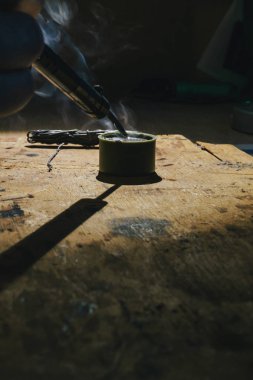 Spotlight ve sıvı reçine gelen duman altında bir sıcak metal lehimleme demir evde çalışma