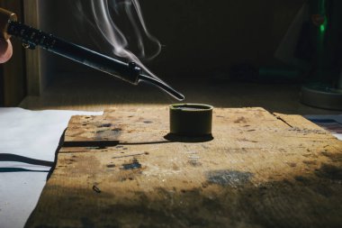 Spotlight ve sıvı reçine gelen duman altında bir sıcak metal lehimleme demir evde çalışma