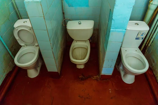 Üç tuvalet kase ve kırmızı boyalı döşeme ile eski umumi tuvalet