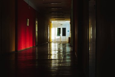 Binanın içinde kırmızı bir duvar ile uzun karanlık bir koridor aydınlatmak batan güneşin ışınları