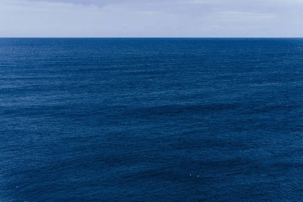 Niekończące się wody niebieski ocean podczas spokojny i pochmurne niebo — Zdjęcie stockowe