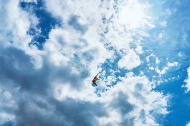 Büyük bir uçurtma yüksek arasında mavi gökyüzü ve parlak yaz güneşi karşı bulutlar gökyüzünde yüzen ve yere gidiş iki beyaz ipleri tarafından kontrol